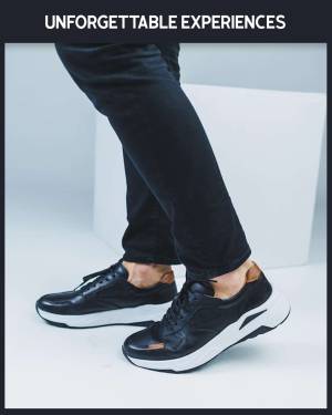 Close-up of a person wearing black leather sneakers with a white sole.