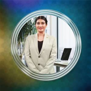 Portrait of a smiling businesswoman in a suit, framed in a silver circle with a blurred office background.