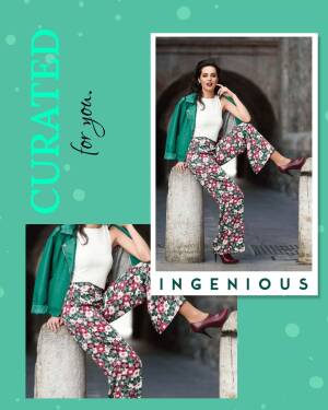 Woman in floral pants and green jacket posing against a stone wall.