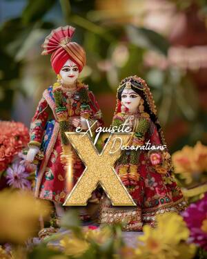 Close-up of Radha Krishna dolls adorned in traditional attire with a blurred floral background.