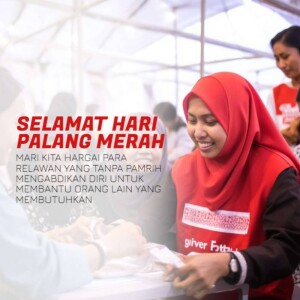 A woman in a red hijab and vest volunteering at a Red Crescent event.