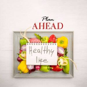 Framed arrangement of colorful vegetables and a notepad with 'Plan Ahead' and 'Healthy Life' written on it.