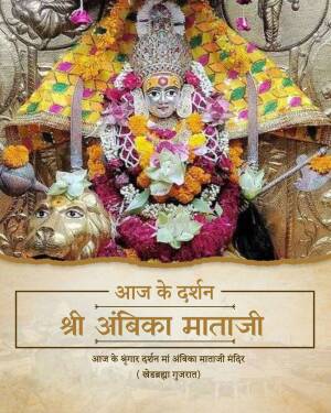 Close-up of the deity Shri Ambika Mataji adorned with flowers and jewelry in a temple setting.