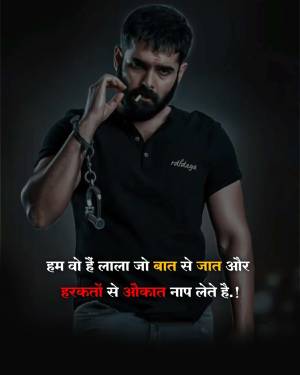 A man with a beard and intense look wearing a black t-shirt with handcuffs and Hindi attitude text