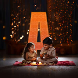 Two young children celebrating Diwali with sweets and lights.