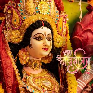 Close-up of a beautifully decorated Durga idol with intricate gold jewelry and vibrant flowers.