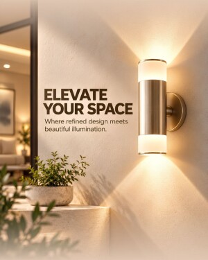 A modern cylindrical metallic wall sconce lamp illuminating a light-colored wall with warm light beams, featuring a plant in the foreground.
