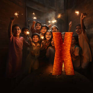 Group of children celebrating Diwali with sparklers and a large illuminated 'X' symbol.