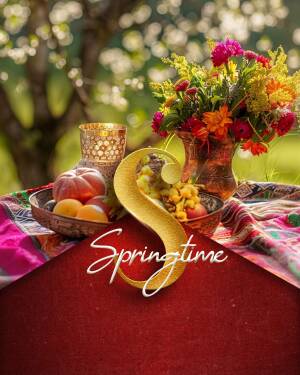A beautifully arranged still life with flowers, fruit, and a golden 'S' for Springtime.