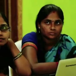 Two focused Indian women observing a laptop screen during a computer training session