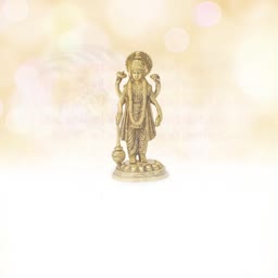 A metallic gold-colored statue of Lord Vishnu standing against a blurred, soft golden bokeh background.