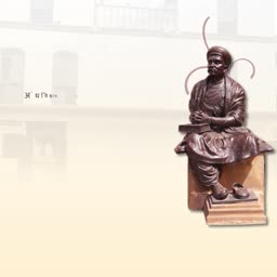 A bronze statue of Saint Tukaram Maharaj seated on a pedestal against a light background.