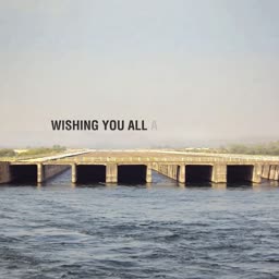A view of a long concrete bridge extending over a river with text overlay Wishing You All A.