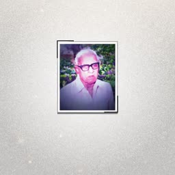 An elderly man wearing glasses in a framed portrait against a sparkling light background