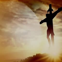 A dramatic silhouette of Jesus crucified on a cross against a glowing golden sunset sky.