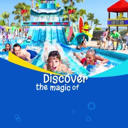 Children sliding down a large water park slide with bright blue water and tropical palm trees in the background