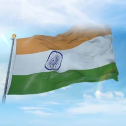 A high-resolution image of the Indian national flag waving against a bright blue sky with light clouds