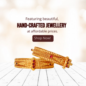 Two intricate gold bangles with red stones on a wooden table surface