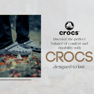 A person wearing gray Crocs clogs standing in a natural forest setting