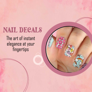 A hand wearing colorful patterned nail decals with donuts, hearts, and rainbows on a pink background.