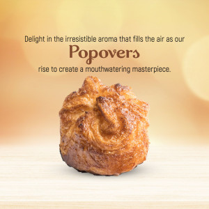 A single golden-brown freshly baked popover on a light wooden surface