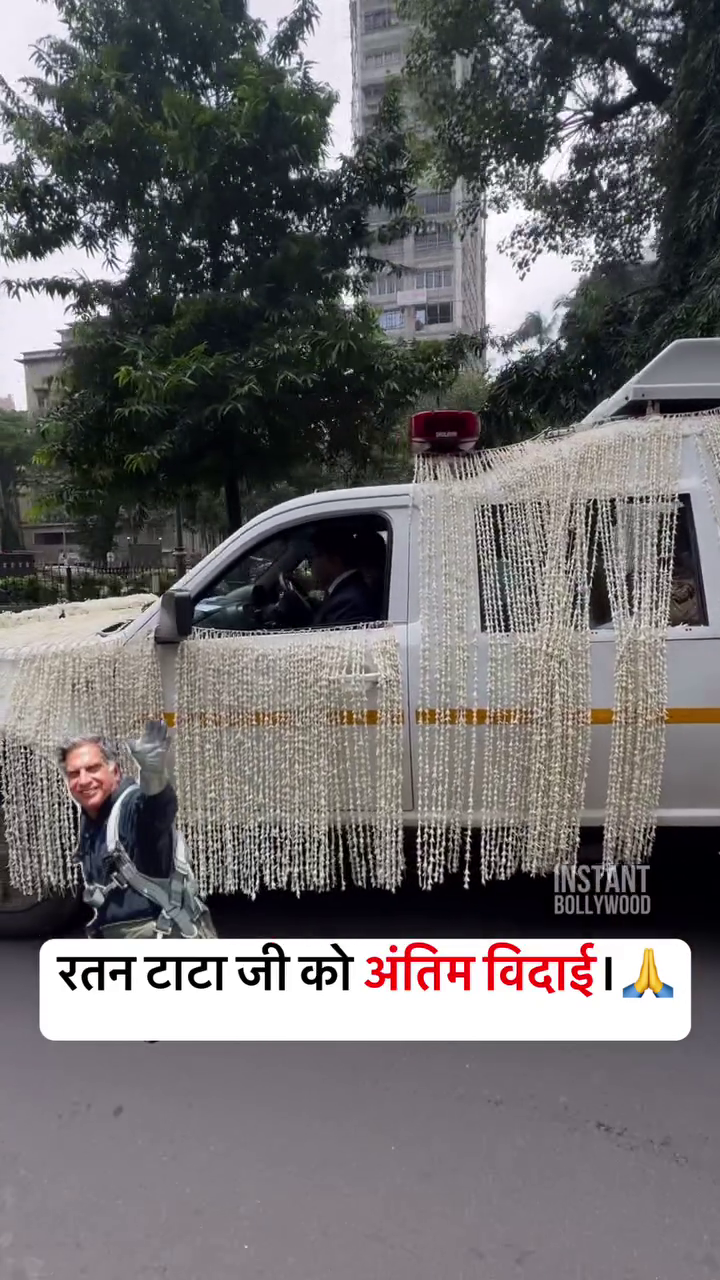 A white vehicle adorned with flower garlands for Ratan Tata's funeral procession with a photo of him waving