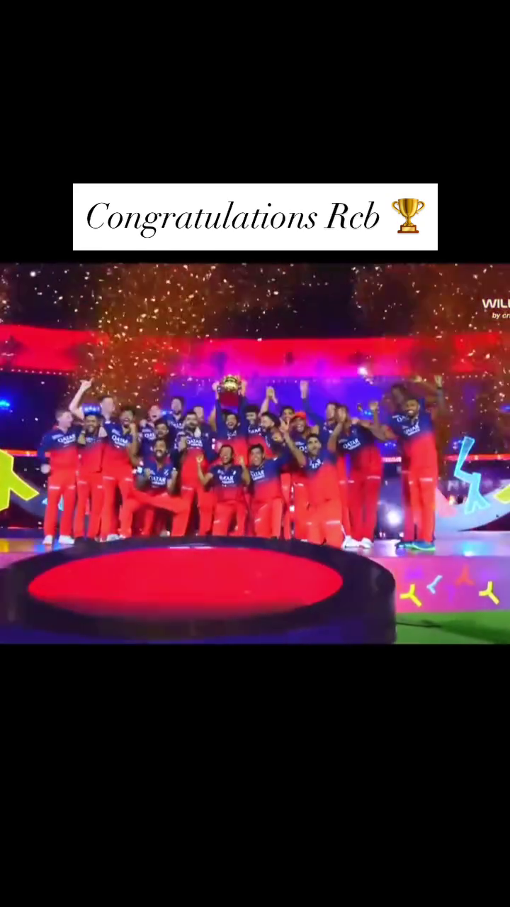 Royal Challengers Bangalore team celebrating victory on stage with trophy