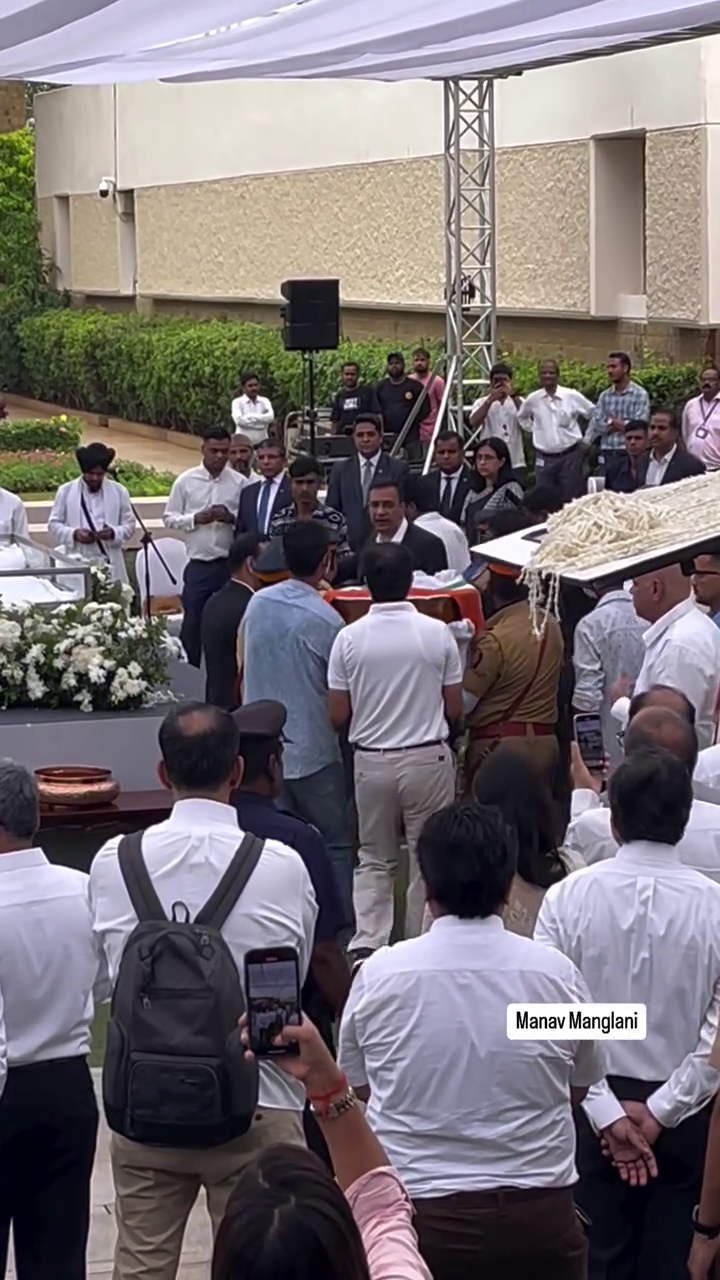 A crowd of people gathered for a funeral procession under a white canopy.