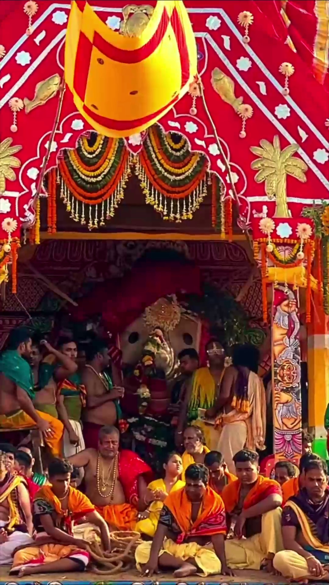 Devotees gathered around the Jagannath deity under a vibrant red and yellow decorated canopy during Rath Yatra.