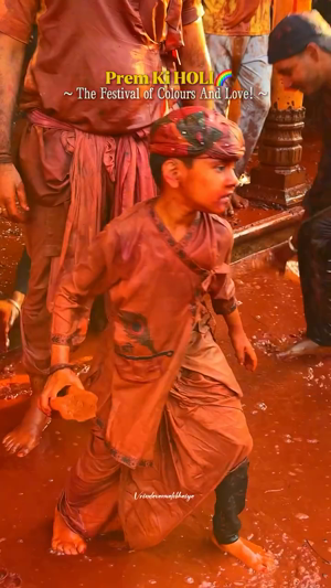 A young boy covered in red gulal color celebrating the Holi festival